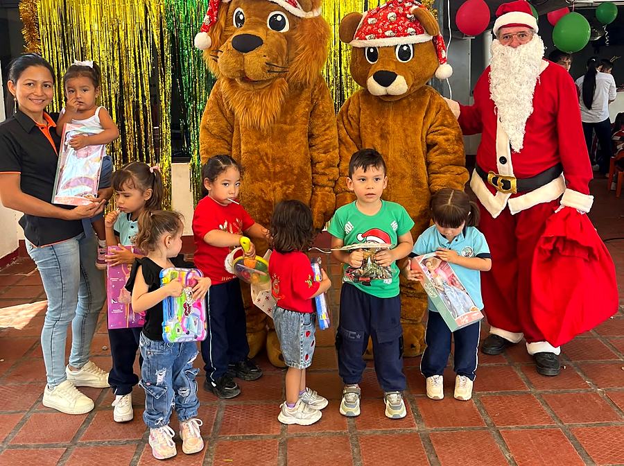 Menores recibiendo regalos junto a Papá Noel y las mascotas del colegio