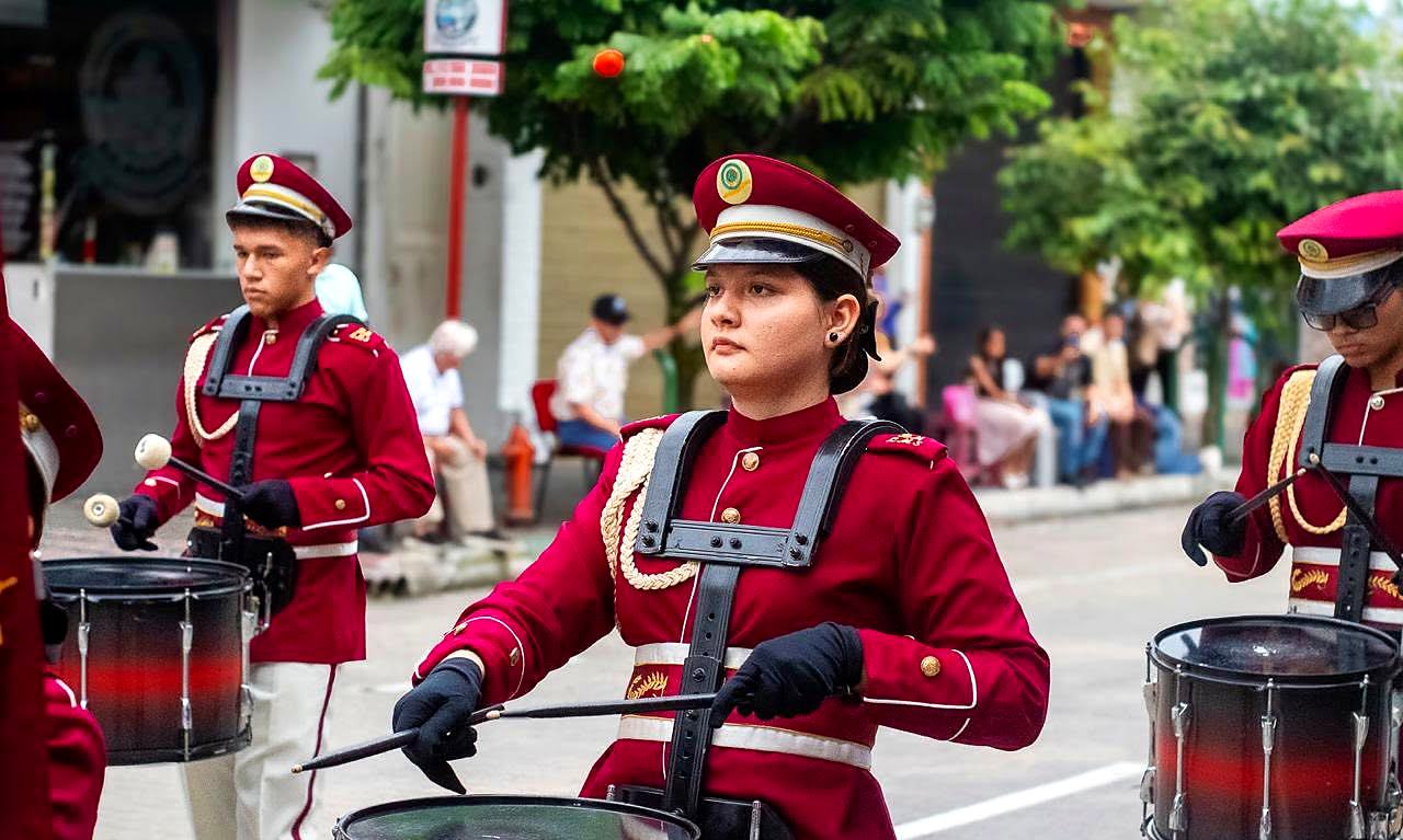 Integrantes de la banda marcial tocando redoblantes en un desfile