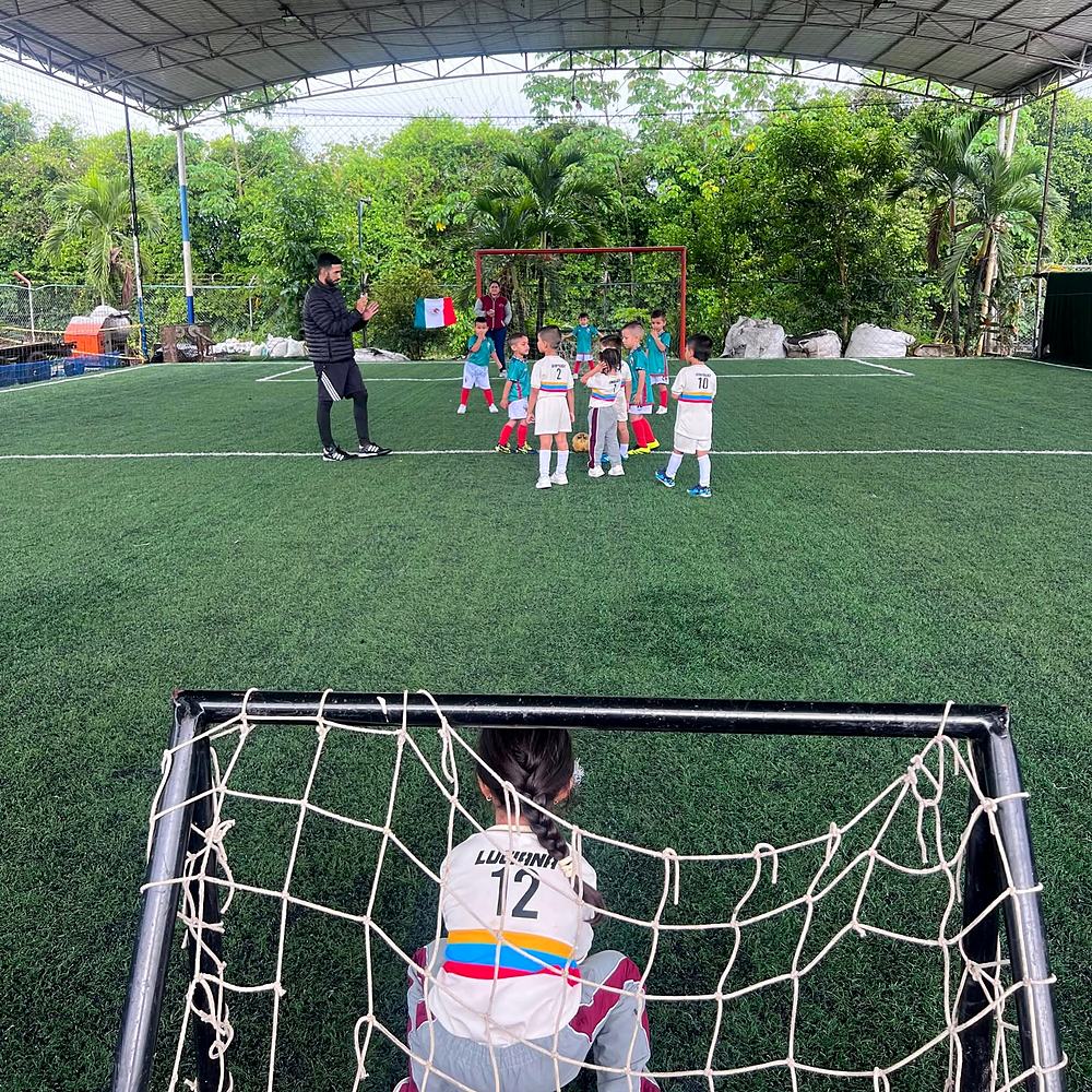 Estudiantes jugando fútbol en la cancha sintética cubierta